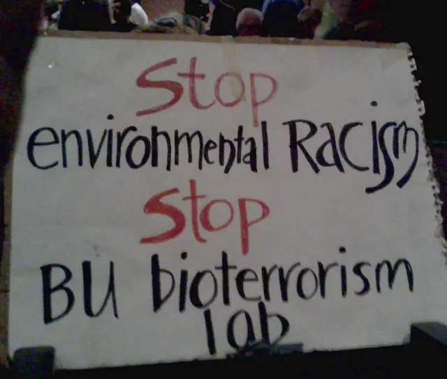 Protest sign against BU's bioterror lab that emphasizes link between bioweapons and environmental racism.